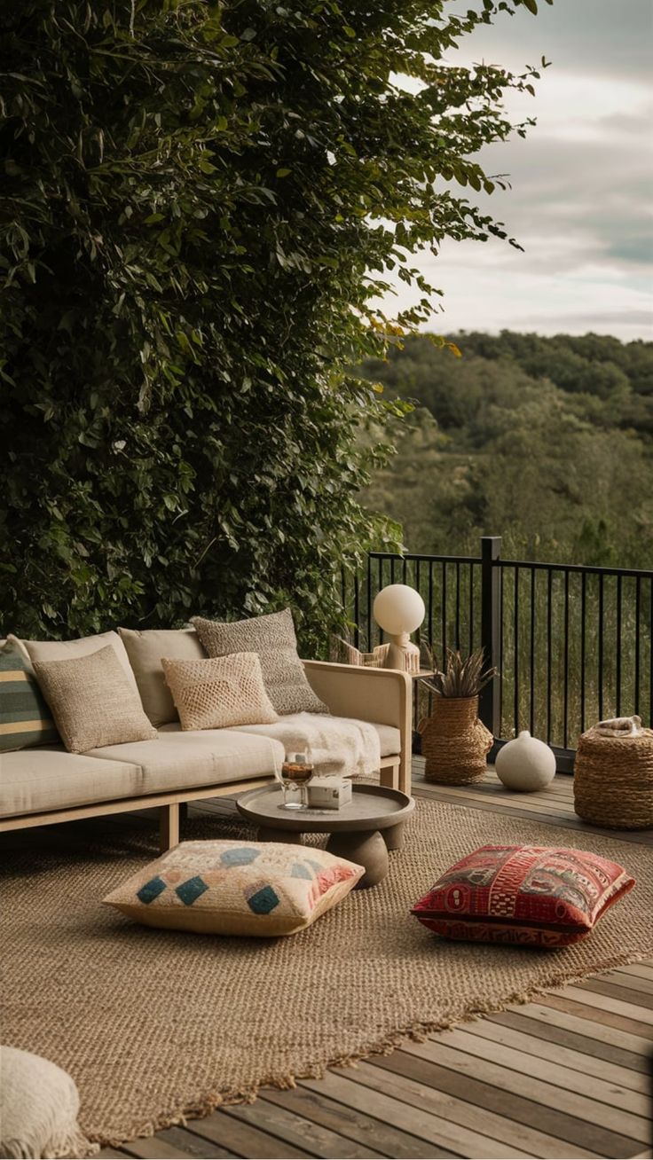 a living room with lots of pillows on the floor and furniture in front of trees