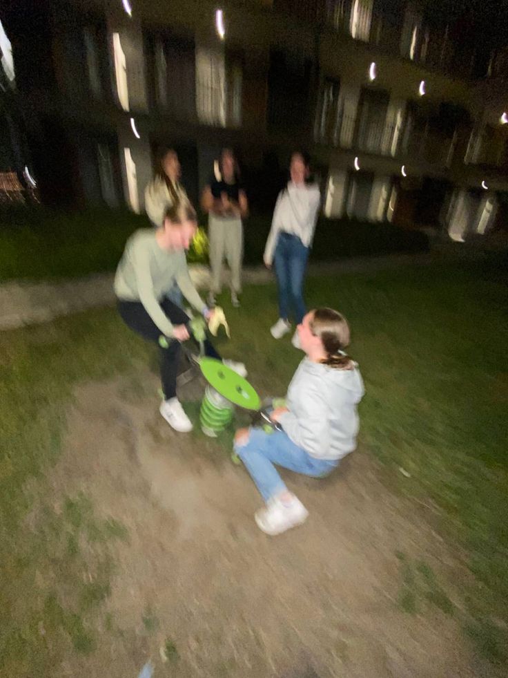 some people are playing in the grass with a green frisbee at night time