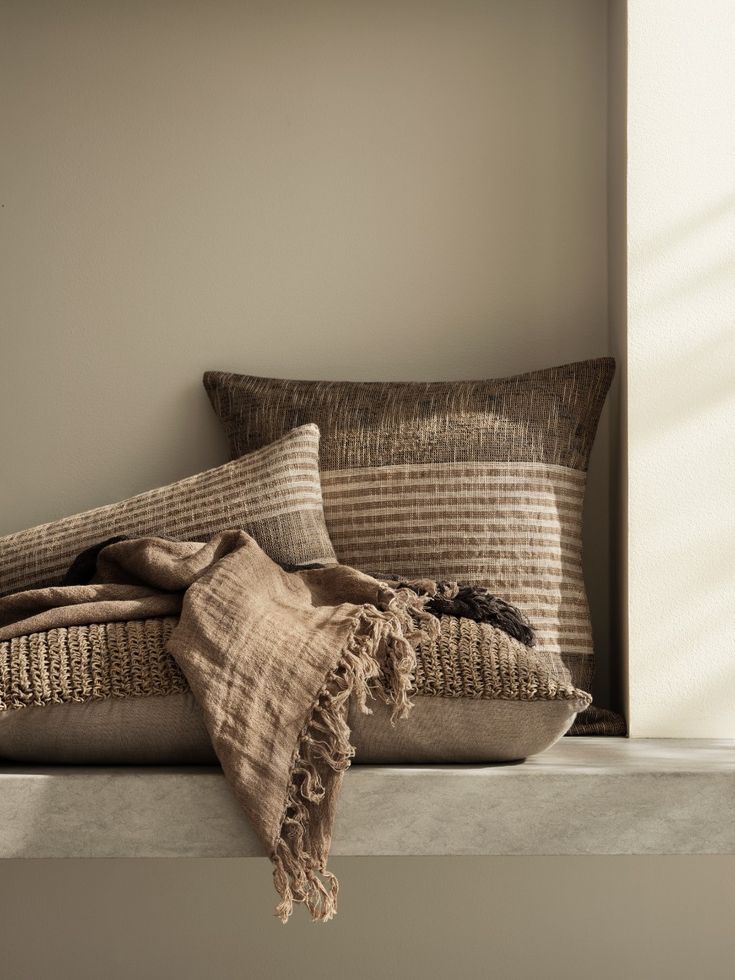 pillows and blankets are sitting on a ledge in front of a window with sunlight streaming through the windowsill