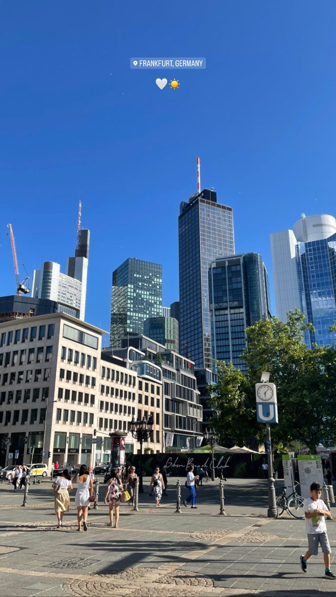 people are walking around in the city with tall buildings and skyscrapers on either side