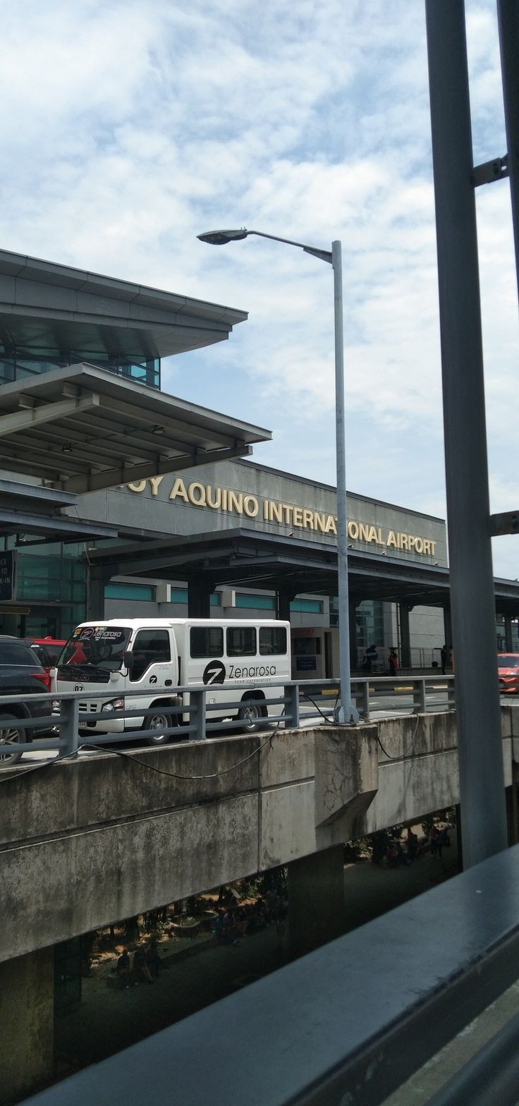 an airport terminal with several vehicles parked on the walkway and in front of it is a bridge