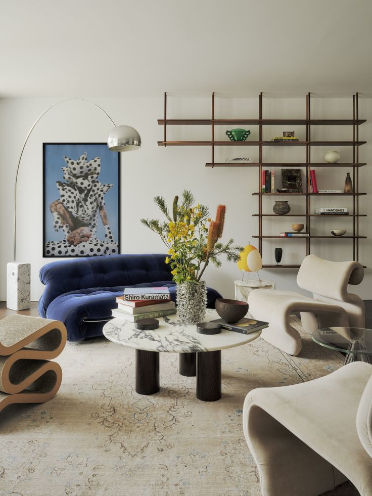 a living room filled with furniture and a painting on the wall above it's coffee table