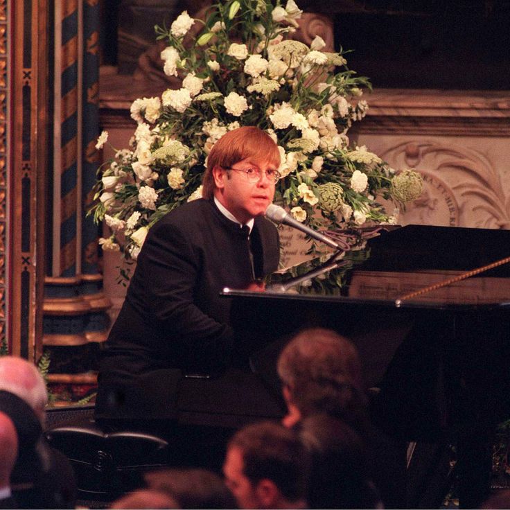 a man sitting at a piano in front of a microphone