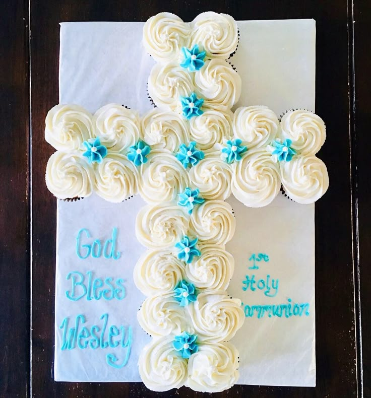 a cross made out of cupcakes sitting on top of a paper towel with blue icing