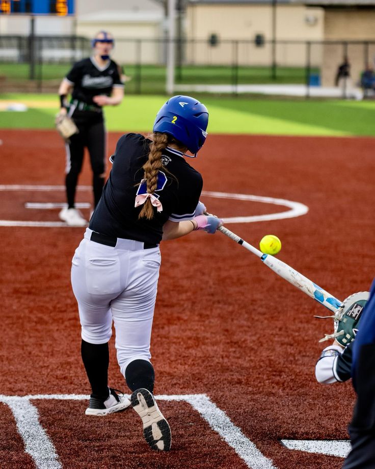 a woman hitting a softball with a bat