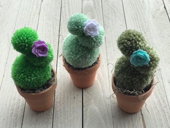 three small potted plants with flowers on them sitting on a wooden surface, one is green and the other is brown