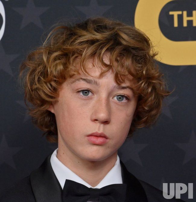 a young boy in a tuxedo and bow tie looking at the camera with an intense look on his face