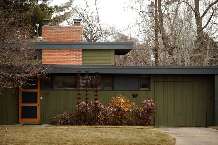 a green and brown house with trees in the background