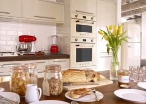 a kitchen with white cabinets and yellow flowers in a vase on the counter top next to bread