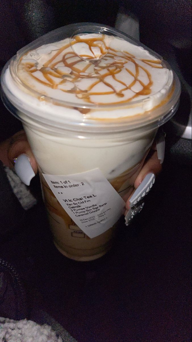 a person holding a cup with caramel swirl on it