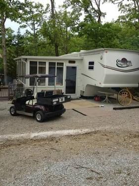 an rv parked in front of a house with a golf cart and buggy on the driveway