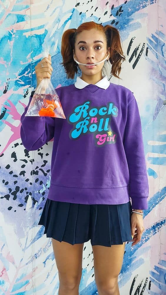 a girl in a purple sweatshirt and black skirt holding a plastic bag with the word rock roll on it