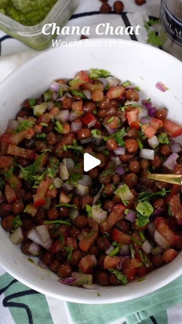 a white bowl filled with beans and veggies on top of a green table cloth