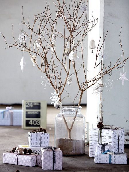 there is a small tree that has been decorated with presents and wrapped in white paper