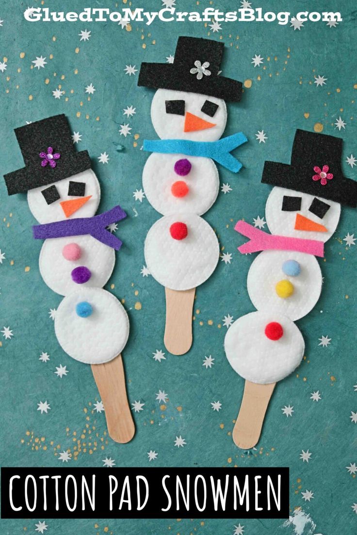 three snowmen made out of popsicle sticks sitting on top of a blue background