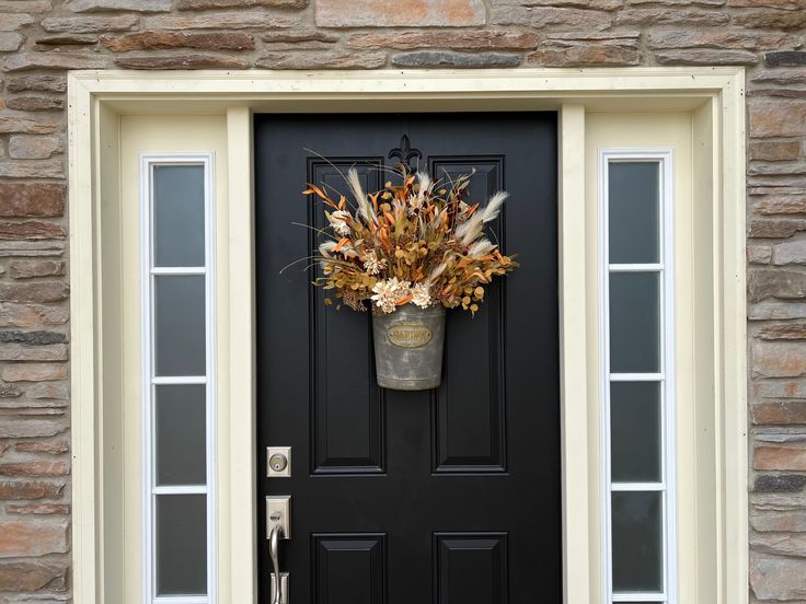 a black front door with an autumn wreath on it