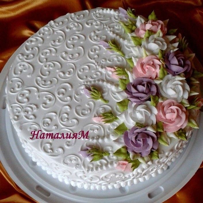 there is a white cake with pink and purple flowers on it