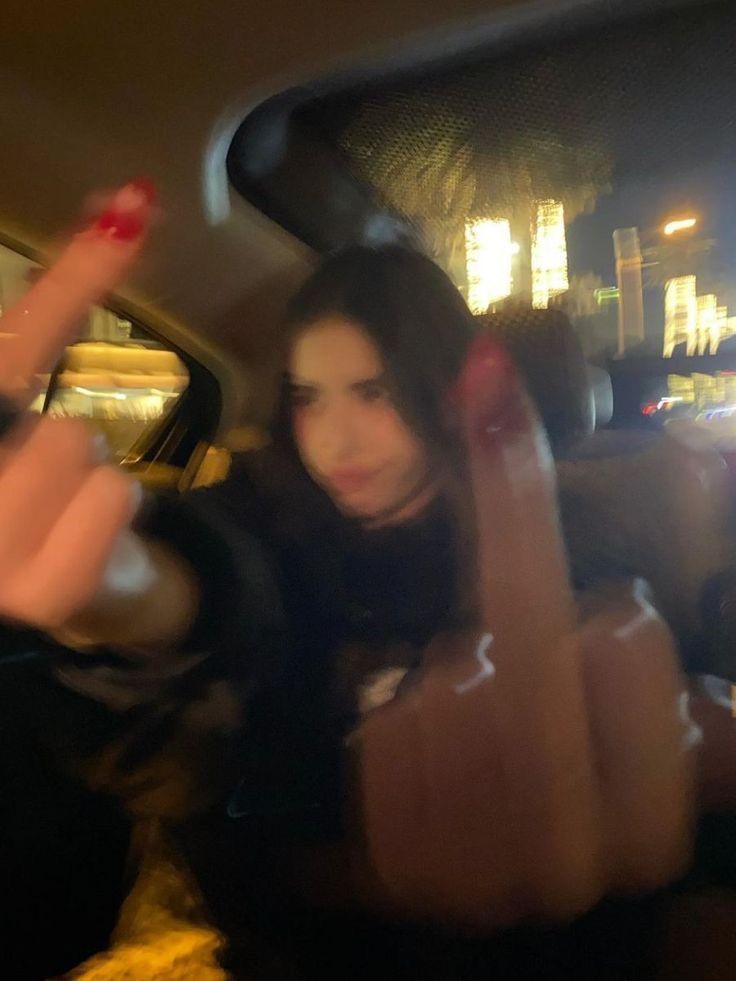 a woman sitting in the back seat of a car pointing her finger at someone else