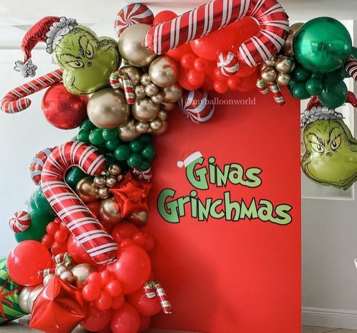 the grinchmas balloon arch is decorated with red, green and gold balloons that read give christmas