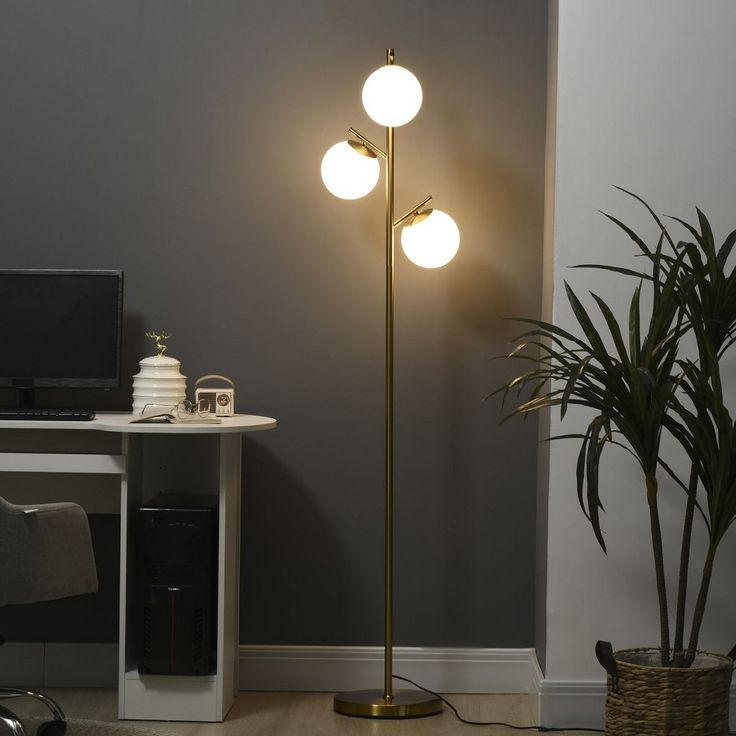 a lamp that is on top of a table next to a potted plant and computer