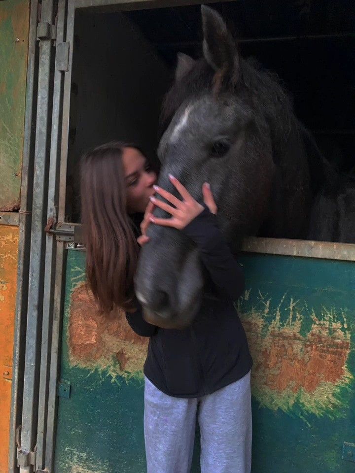 a woman standing next to a horse in a stable