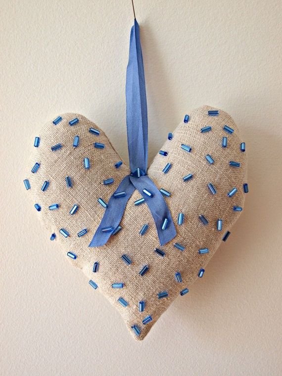 a heart shaped ornament hanging on a wall with blue ribbon and sprinkles