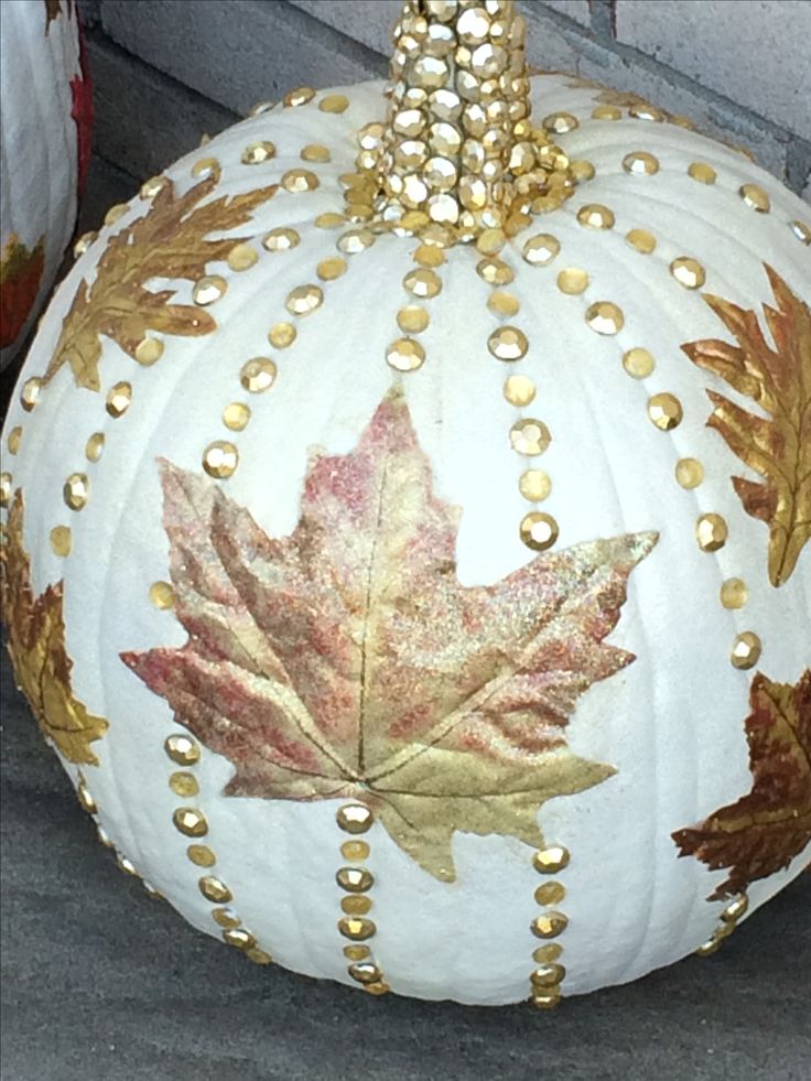 a large white pumpkin decorated with gold leaves