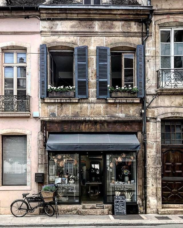 an old building with shuttered windows and a bicycle parked in front of the window