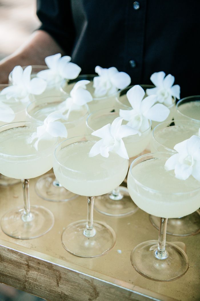 there are many glasses with drinks in them on the tray and one is filled with white flowers