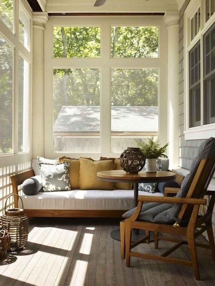 the sun shines through the large windows onto an enclosed porch with a couch and table