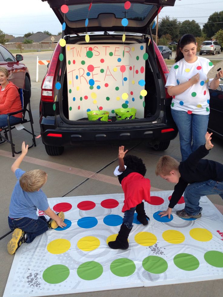 two adults and three children playing with an inflatable dot mat on the ground