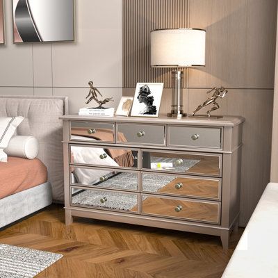 a bedroom with a bed, mirror dresser and lamp on the side table in front of it