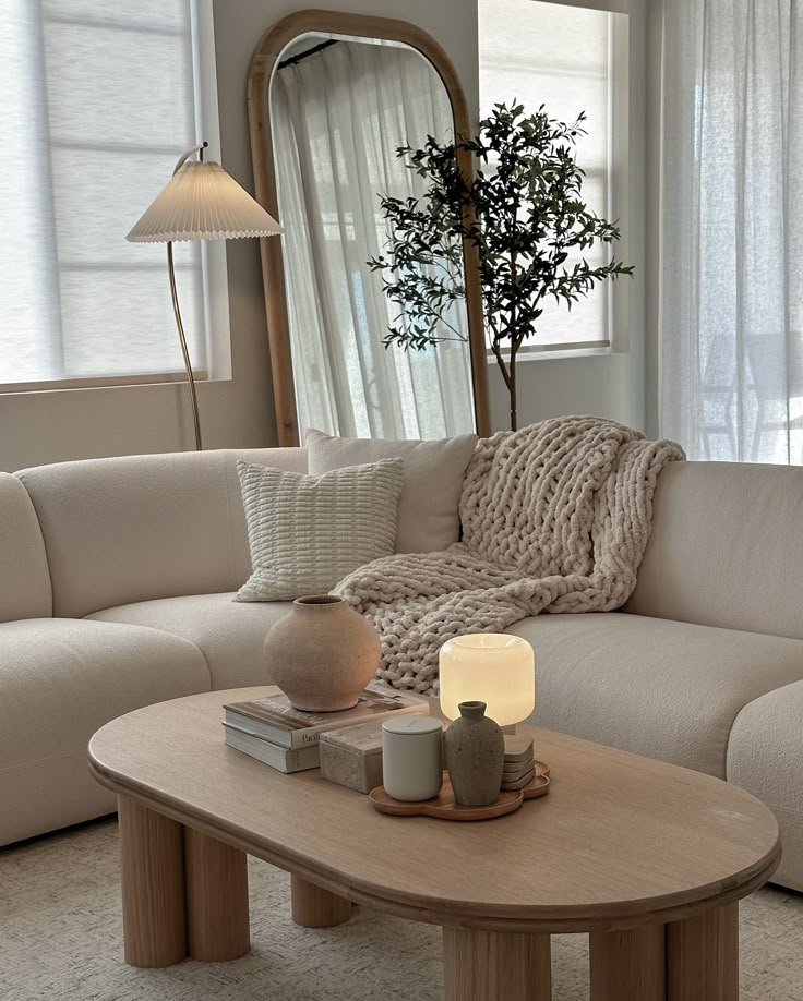 a living room with a couch, coffee table and mirror on the wall in front of it