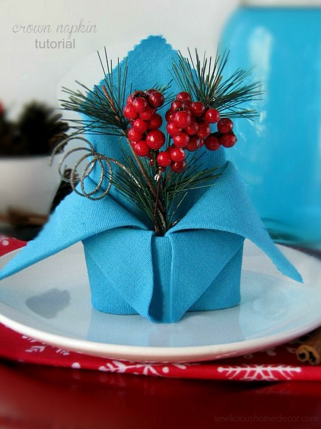 an origami christmas decoration with berries and pine branches on a blue paper napkin