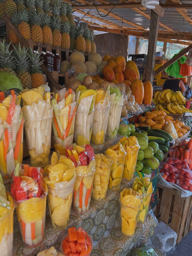 many different types of fruits and vegetables on display at a market stall, including pineapples, melons, bananas, oranges, watermelon, and more