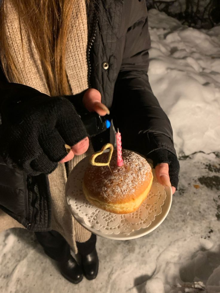 a person holding a plate with a cake on it and a candle in the middle