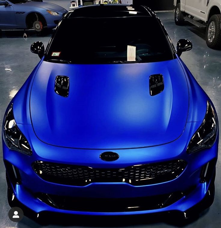 a blue car parked in a garage next to other cars