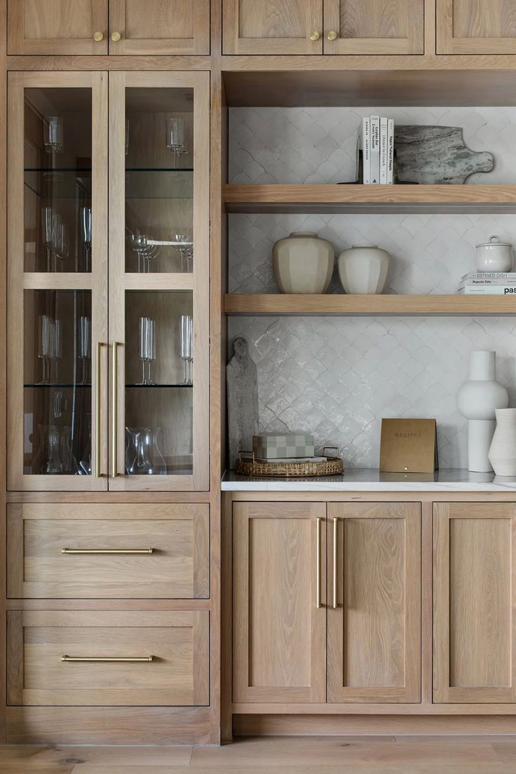 a wooden cabinet with glass doors and shelves filled with vases, dishes and other items