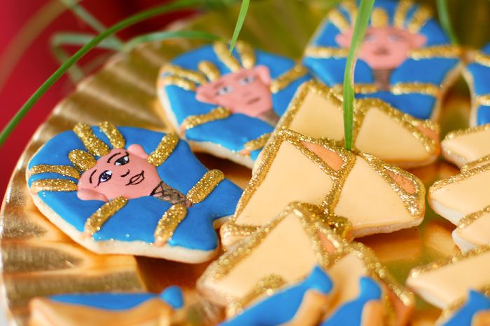 decorated cookies with blue and gold icing on a plate in the shape of boxes