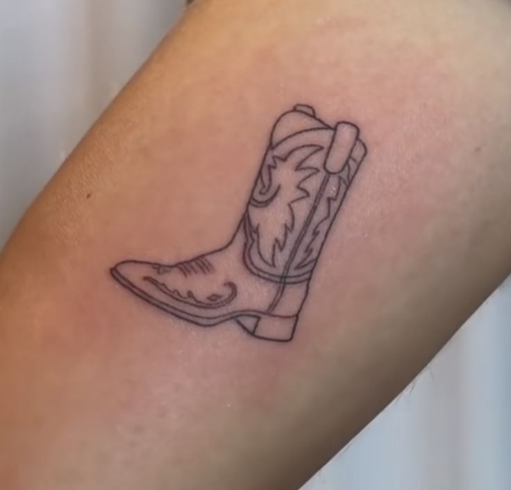 a small tattoo of a cowboy boot on the right thigh, with an arrow in the center