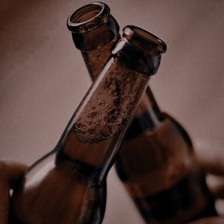 two empty beer bottles being held by someone's hand