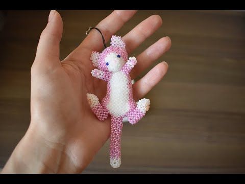 a hand holding a tiny pink and white cat ornament on it's palm