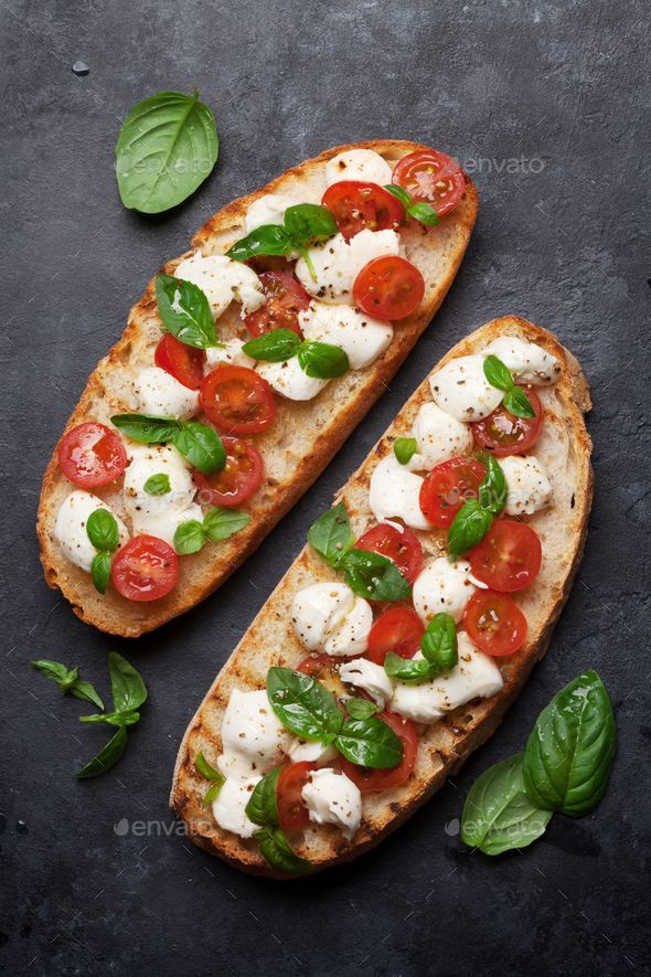 two slices of bread with tomatoes, mozzarella and basil on top - stock photo - images