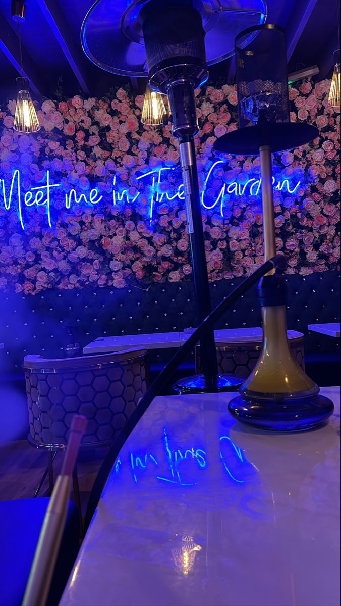 the neon sign is lit up on the wall behind the table and chairs in the restaurant