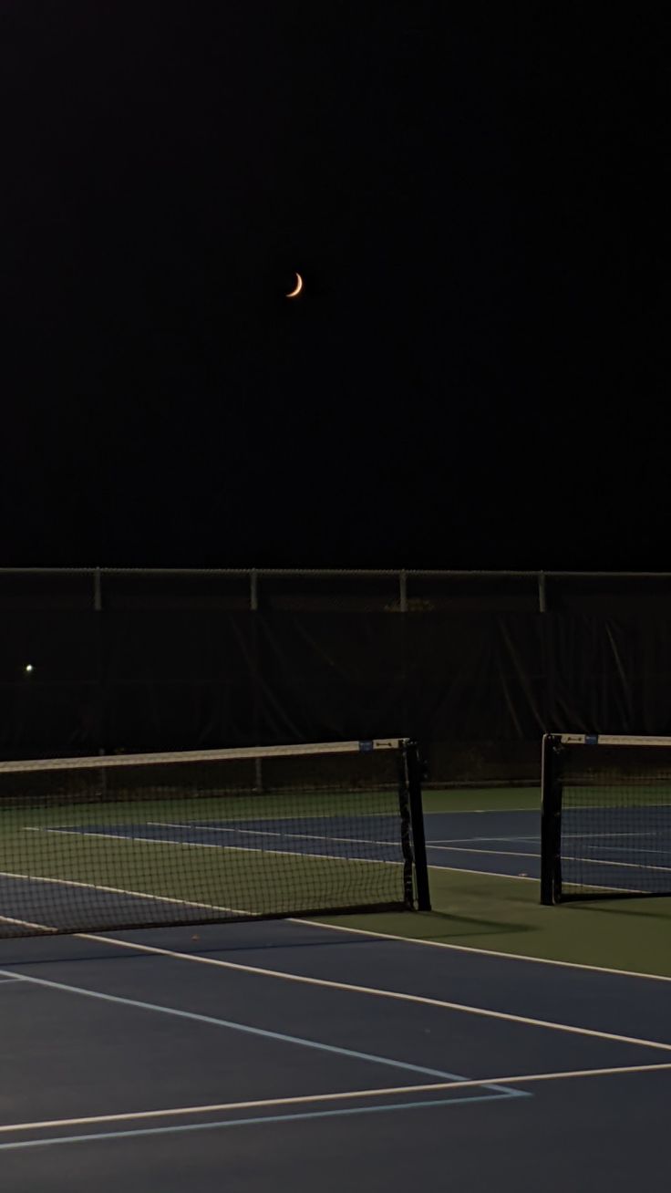 two tennis players are on the court at night with their racquets in the air