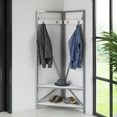 a coat rack with two coats hanging on it next to a potted plant and window