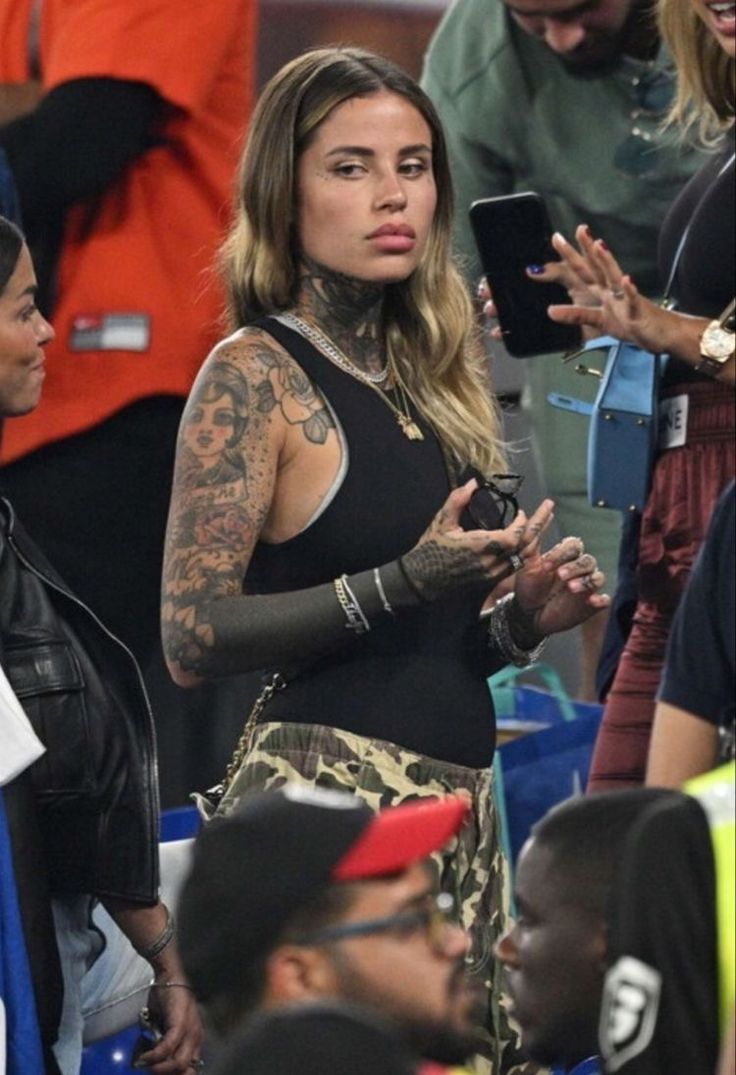 a woman with tattoos is standing in the stands