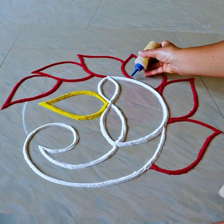 someone is drawing on the ground with crayons and glue to create a flower