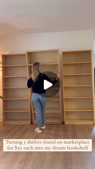 a woman is standing in front of bookshelves and pointing to the wall with her hands