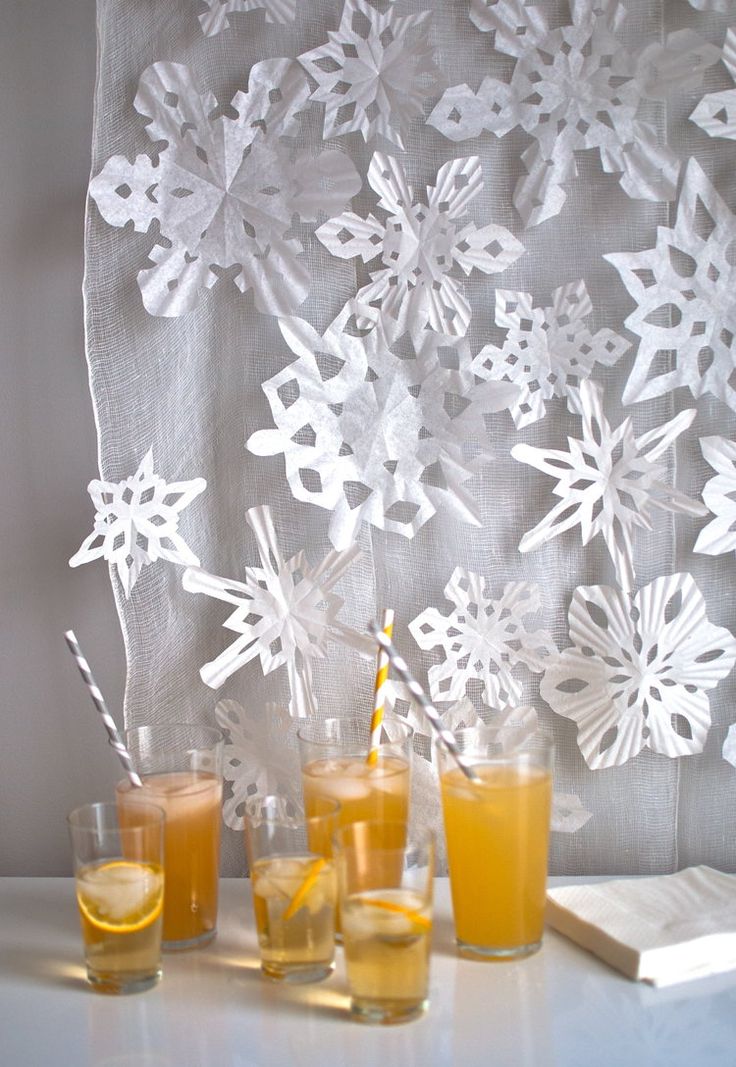 three glasses filled with drinks sitting on top of a table next to a wall covered in snowflakes